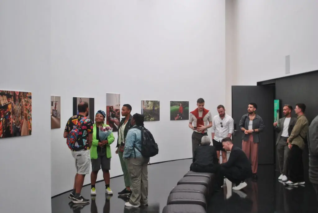 Groups of people talking in a gallery with the exhibition in the background