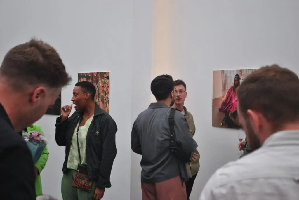 People chatting in front of pictures from the exhibition.