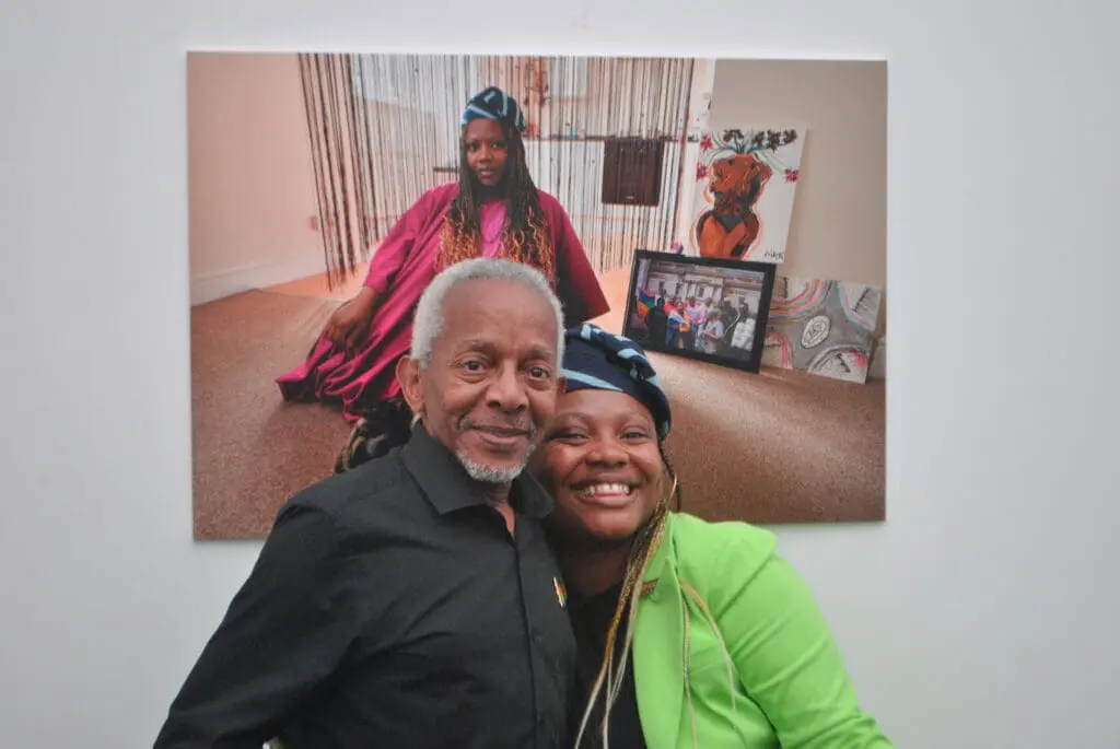 Ted Brown and Jawadat Bashorun smiling in front of Jawadat's portrait from the exhibition