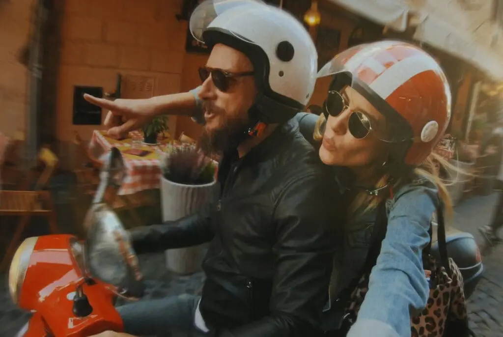 Two people on a motorbike riding through Rome