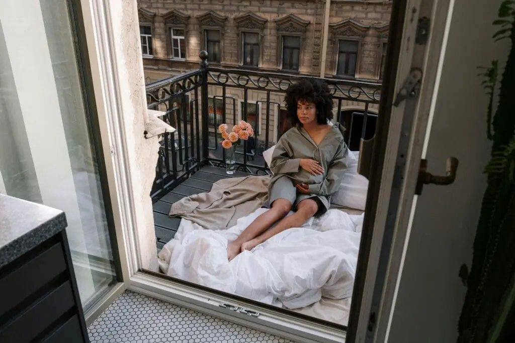 Woman sat with bedding on balcony