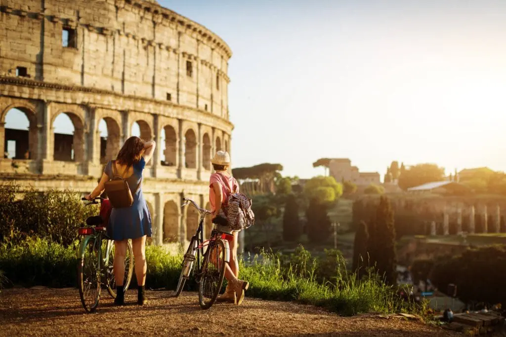 Couple riding bikes looking at the Colosseum in Rome