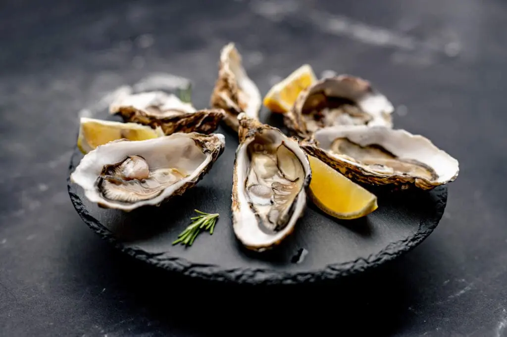 Oysters served with lemon on black round platter
