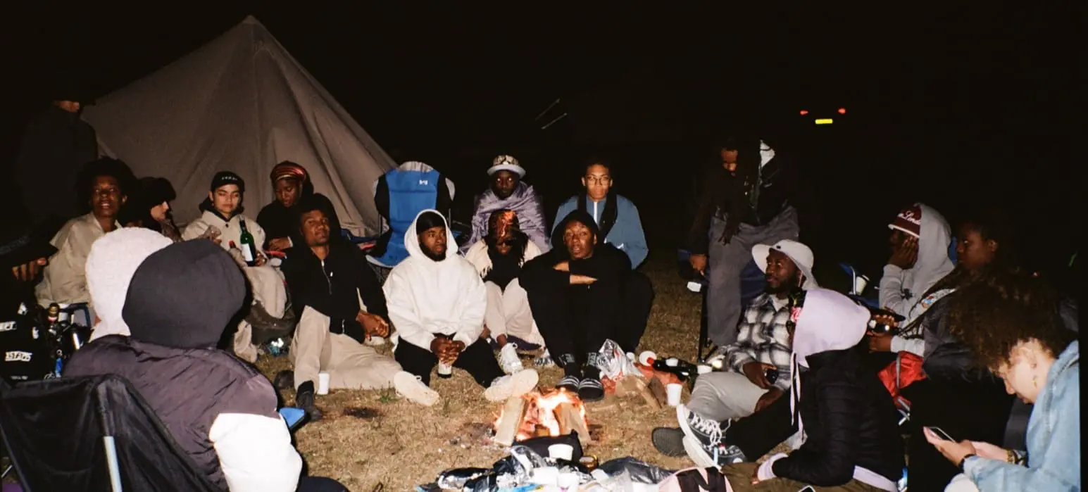 Group of people from Kez Camps Black Camping Club at night, sat around a camp fire