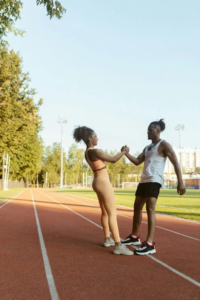 Two people from TrackMafia warming up at a running track in London