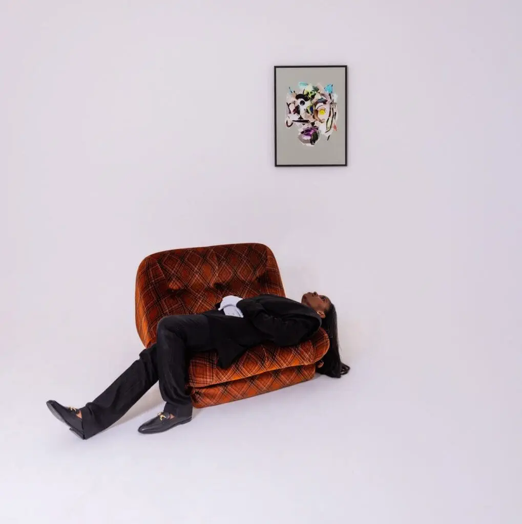 A person lying on a chair looking up at a piece of artwork