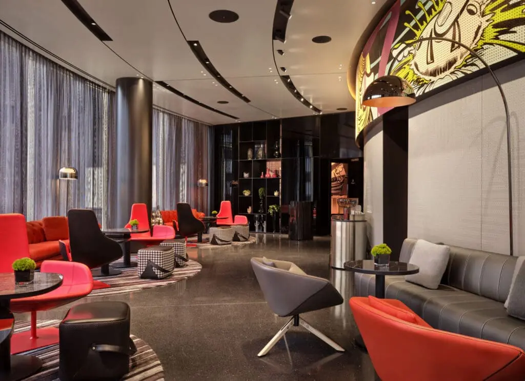 Modern hotel lounge with vibrant red chairs, stylish decor, and pop art wall design at art'otel London Hoxton