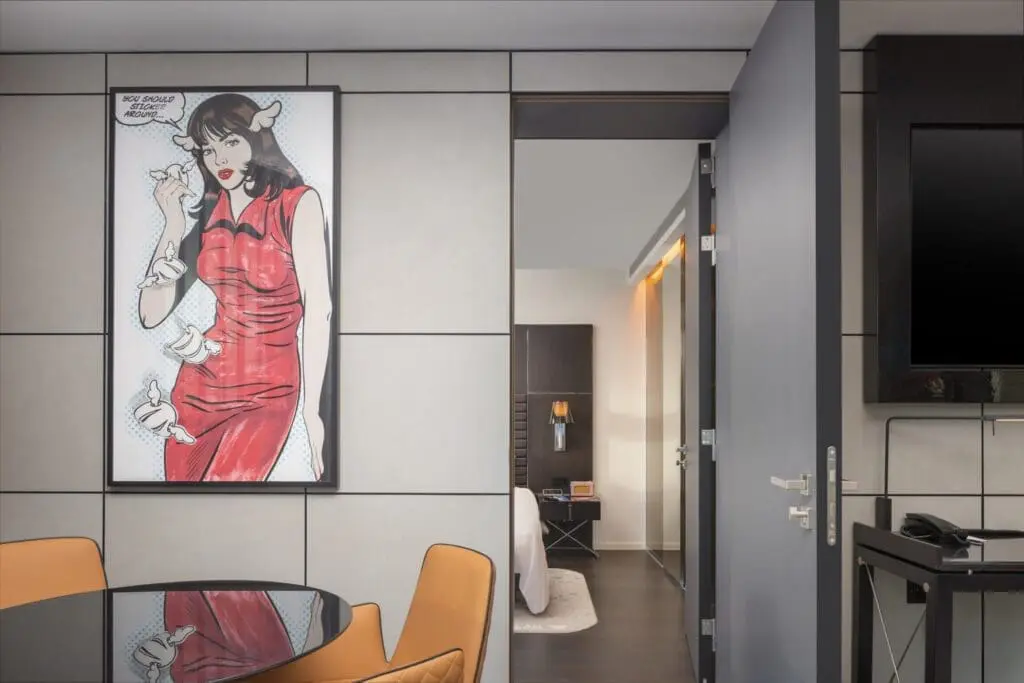 Modern hotel room at art'otel London Hoxton Shoreditch hotel with spa, featuring pop art wall decor and stylish contemporary furniture.