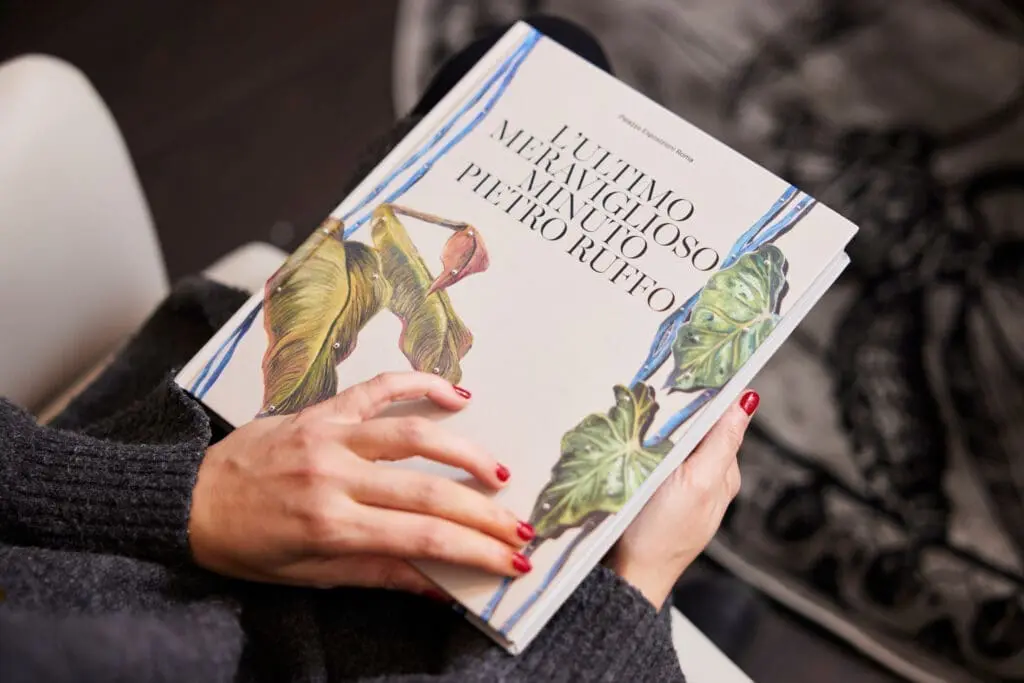 Person holding an art book with botanical illustrations at art'otel Rome art hotel, showcasing elegant design and artistic ambiance.