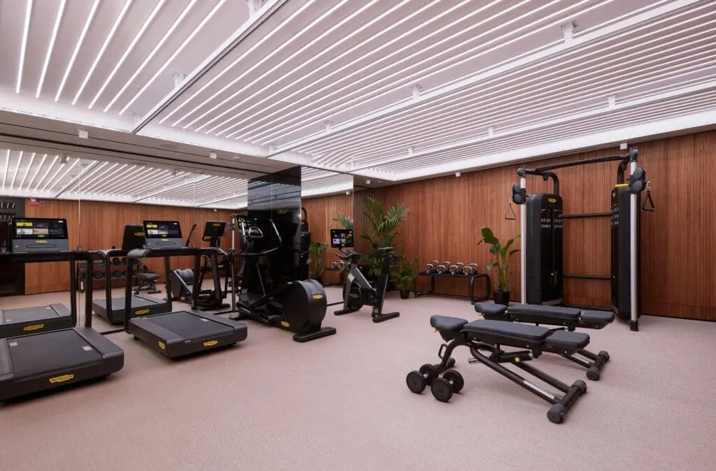 Modern fitness center at art’otel Rome art hotel with treadmills, weight machines, benches, and wooden wall design.