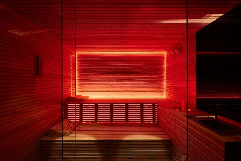 Luxury spa sauna at art’otel Rome art hotel featuring modern wooden interior and vibrant red LED lighting.