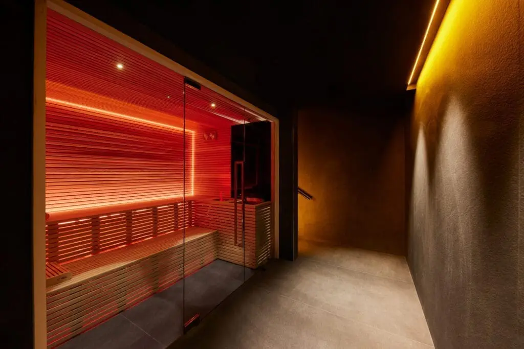 Luxurious sauna with warm red and amber lighting at art'otel Luxury art hotel Rome.