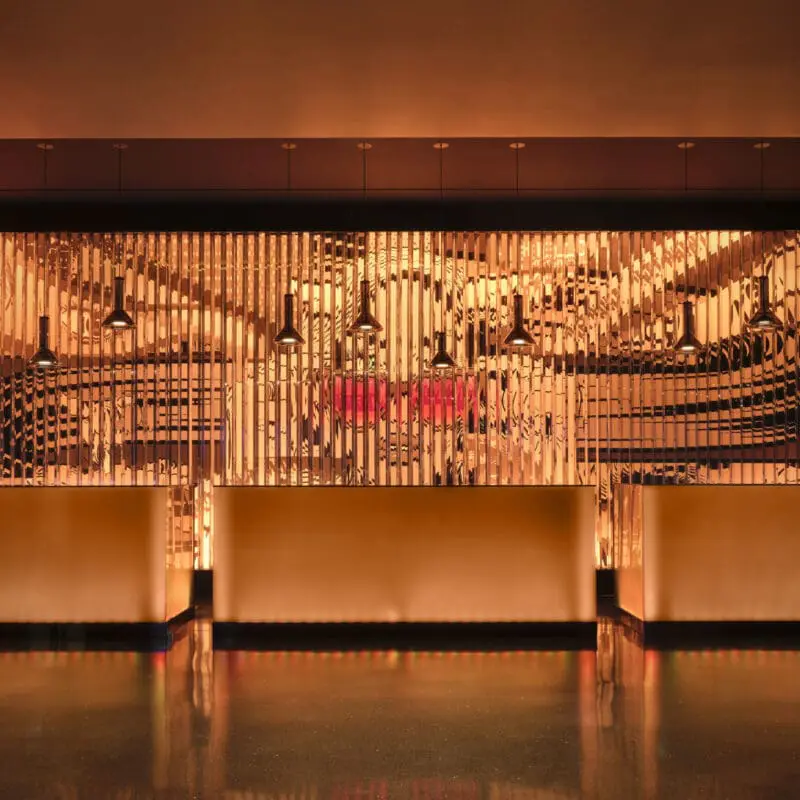 Elegant reception area at art'otel London Hoxton Shoreditch hotel with pool, featuring warm golden lighting and modern artistic wall design.