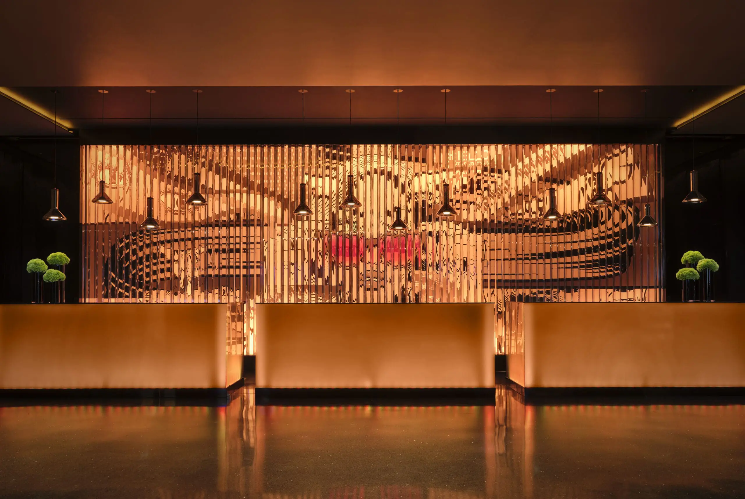Elegant reception area at art'otel London Hoxton Shoreditch hotel with pool, featuring warm golden lighting and modern artistic wall design.