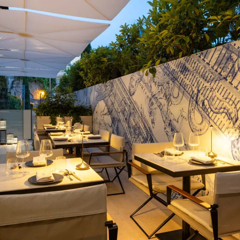 Outdoor dining area at art'otel Yezi restaurant Rome featuring elegant tables, modern decor, and artistic wall design.