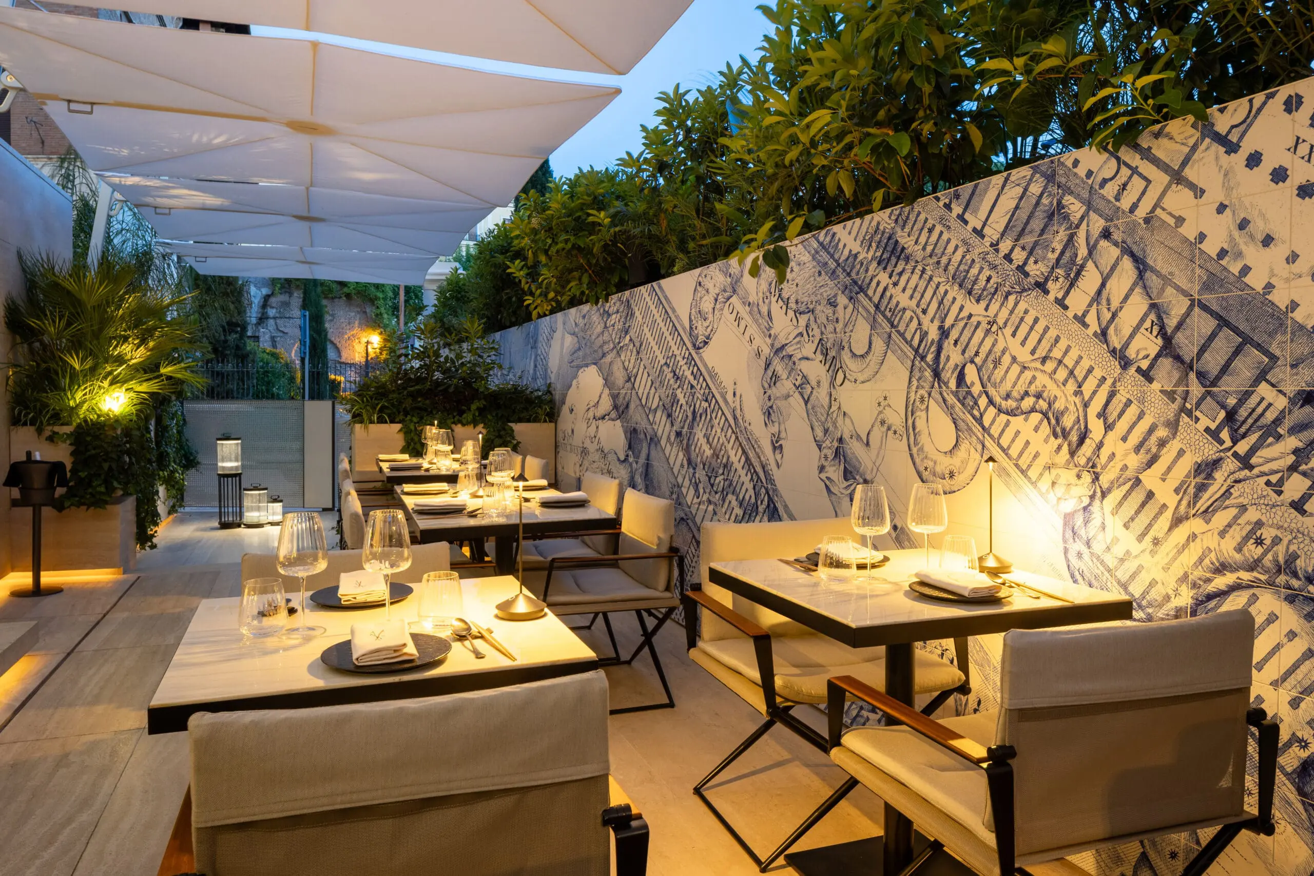 Outdoor dining area at art'otel Yezi restaurant Rome featuring elegant tables, modern decor, and artistic wall design.