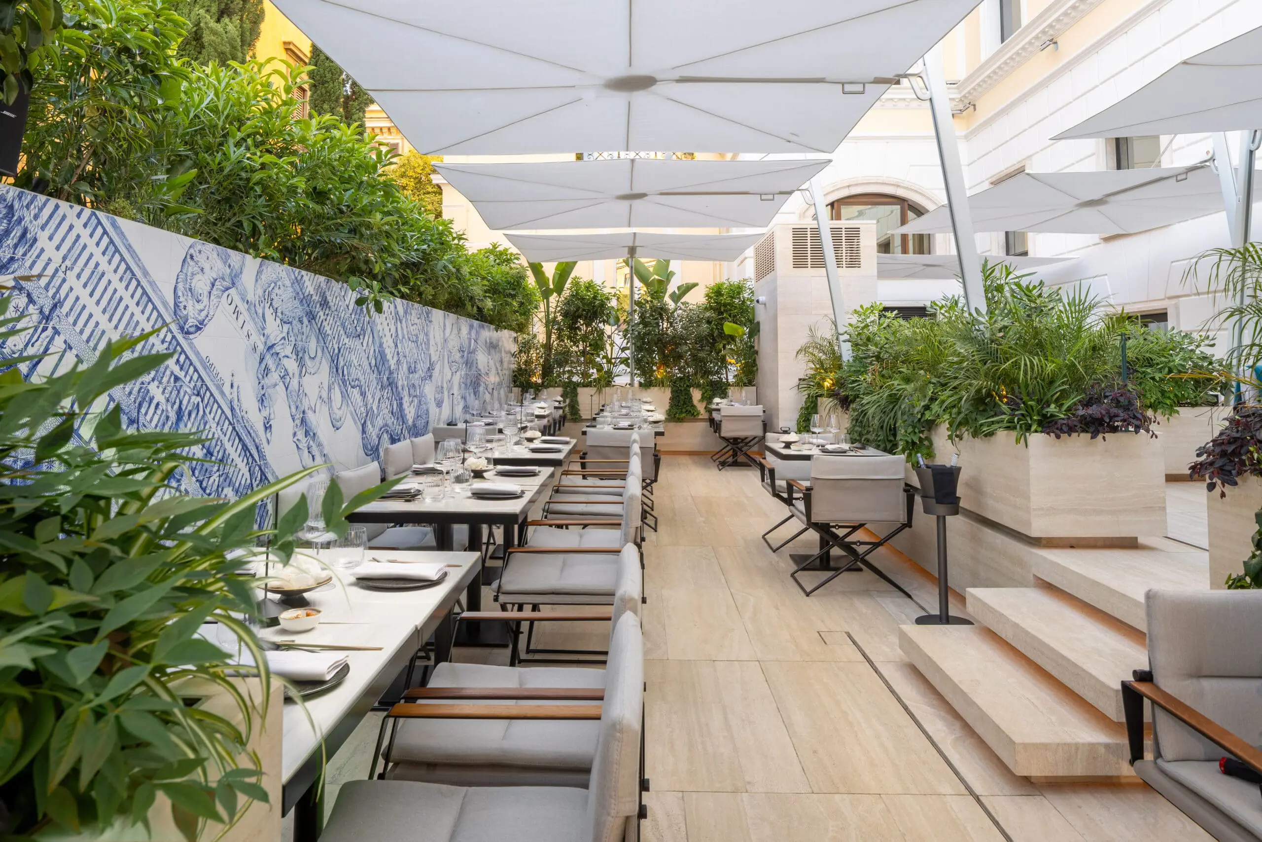 Stylish outdoor dining space at art'otel Luxury art hotel Rome with elegant seating, lush greenery, and artistic wall design.