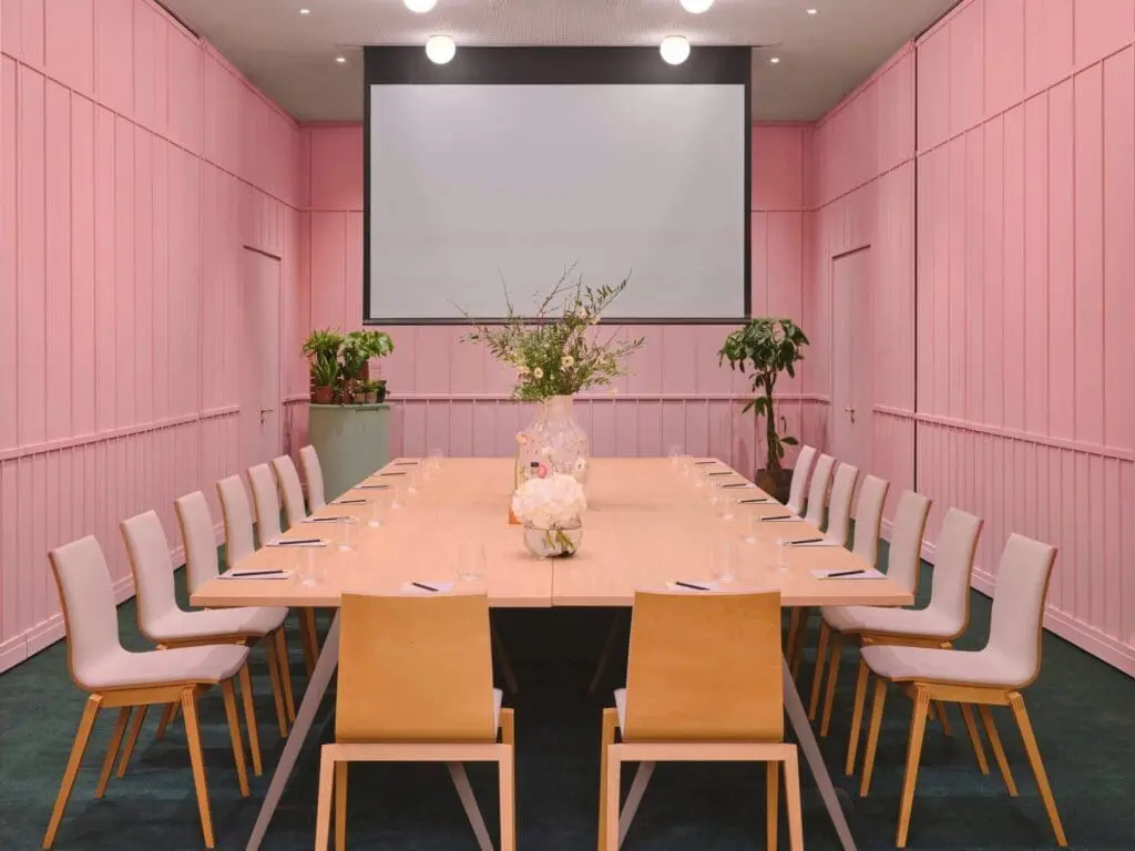Stylish meeting room at art'otel Battersea Power Station meeting to hire featuring pink walls, modern table setup, and elegant decor.