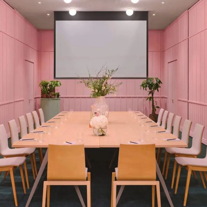 Stylish meeting room at art'otel Battersea Power Station meeting to hire featuring pink walls, modern table setup, and elegant decor.
