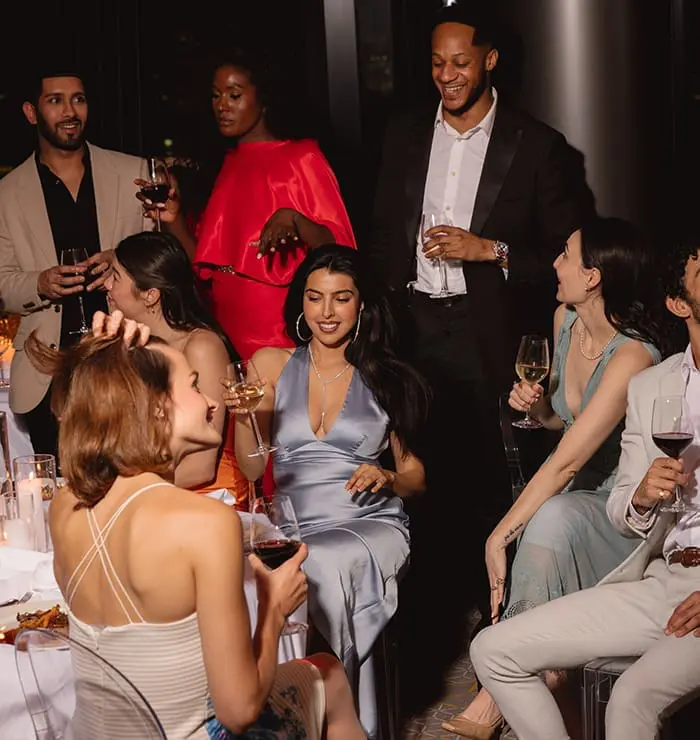 Group of people dressed elegantly enjoying wine at a stylish dinner event in art'otel London Hoxton Old Street hotel with spa