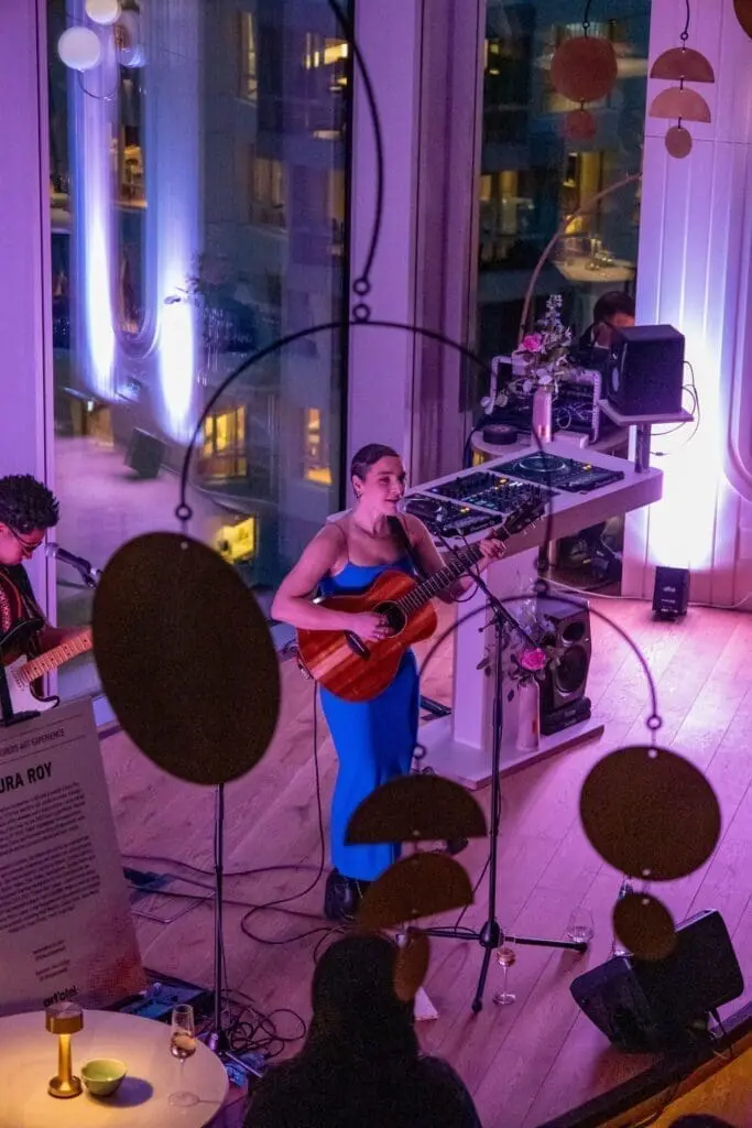 Musician playing acoustic guitar at rooftop bar Perola Battersea Power Station with DJ setup