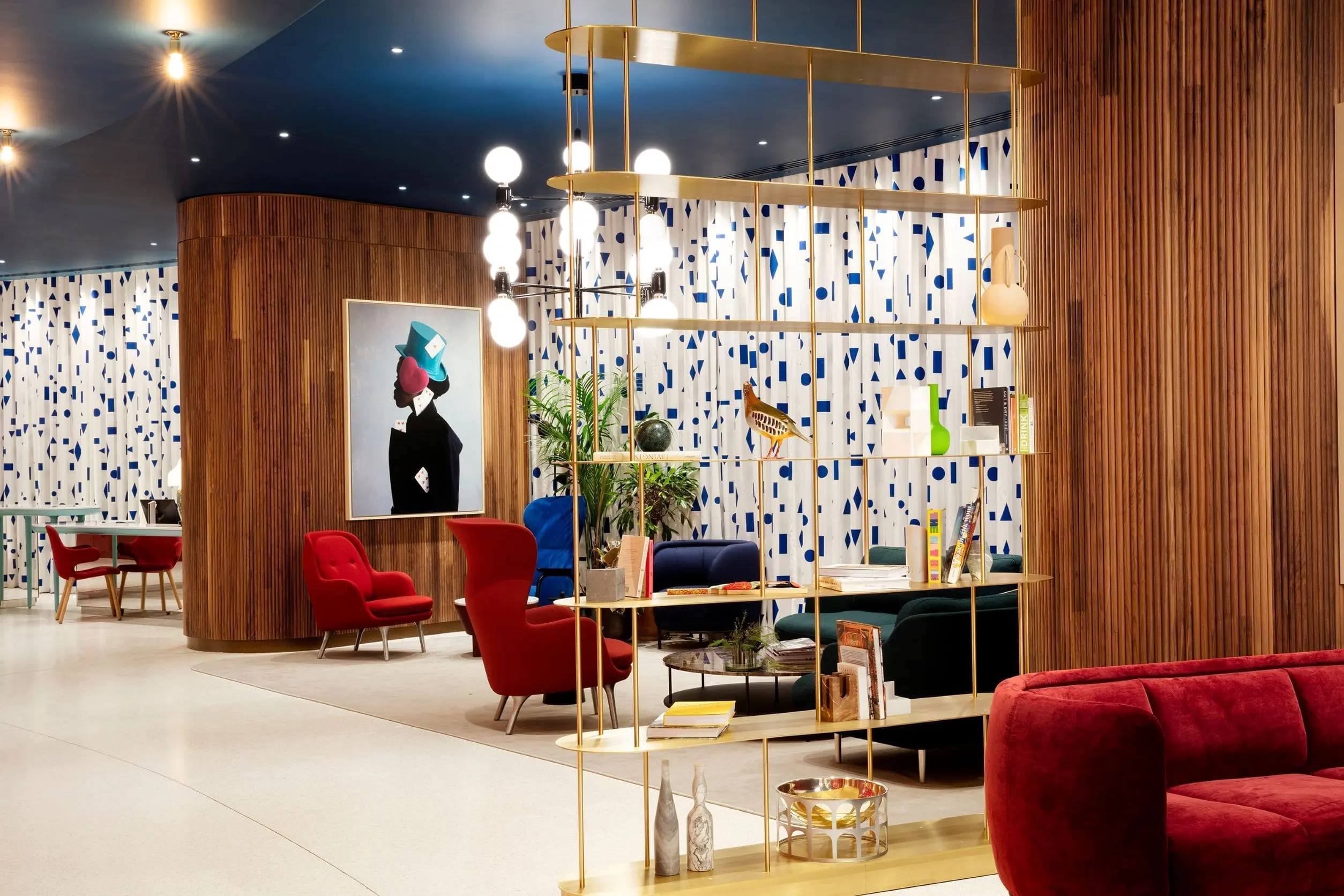 Colourful lounge area with modern seating, bold artwork and decorative shelving inside the art'ote Battersea Power Station view room hotel space.