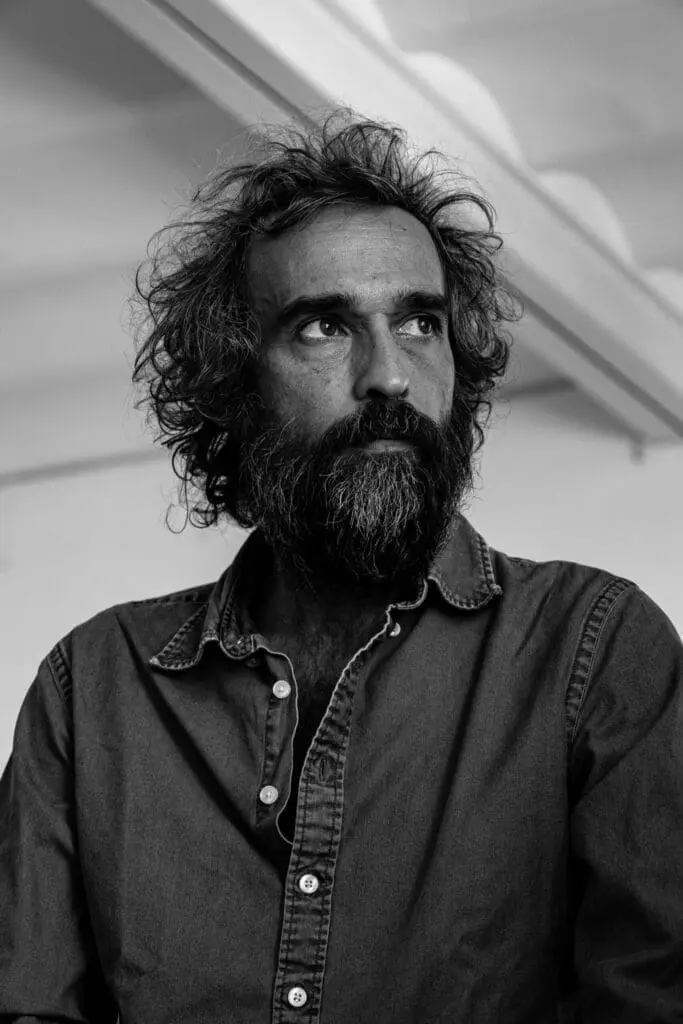 Black and white portrait at art gallery art’otel hotel Rome featuring Pietro Ruffo in casual denim shirt with curly hair.