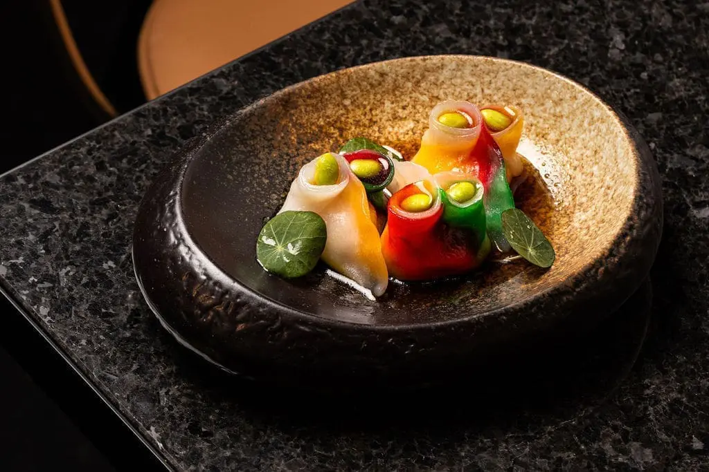 Colorful gourmet dim sum served on a textured ceramic plate at art'otel Yezi restaurant Rome, showcasing artistic culinary presentation.