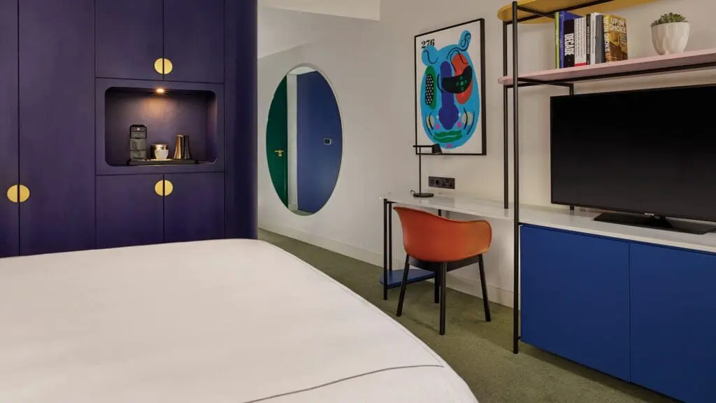 Contemporary guest room at art'otel Battersea Power Station featuring vibrant decor, work desk, coffee station, and stylish modern furniture.