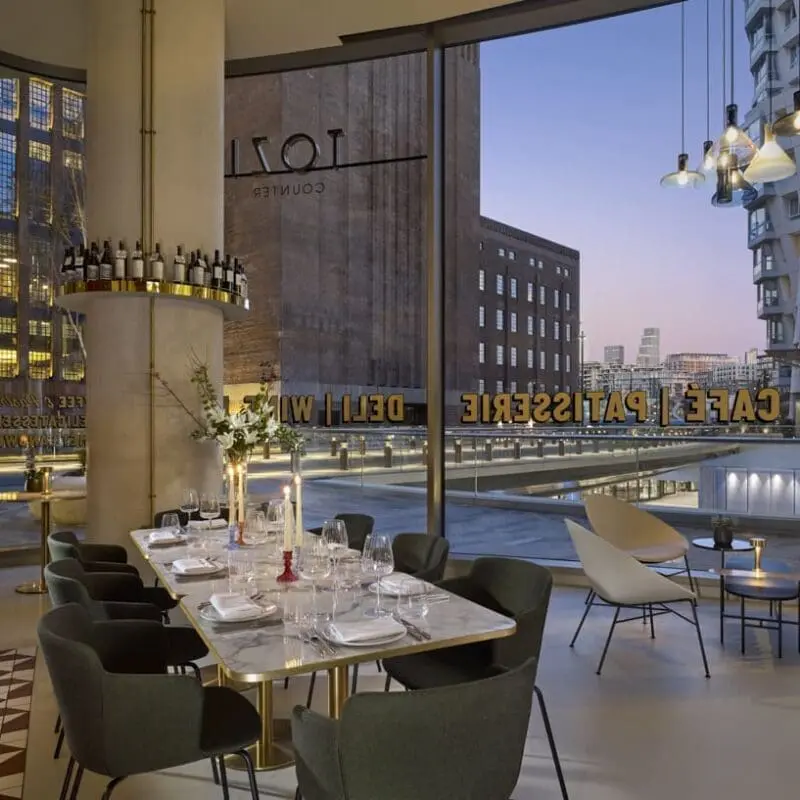 Chic dining space at art'otel Battersea Power Station restaurant & bar featuring marble table, modern chairs, and panoramic city views.