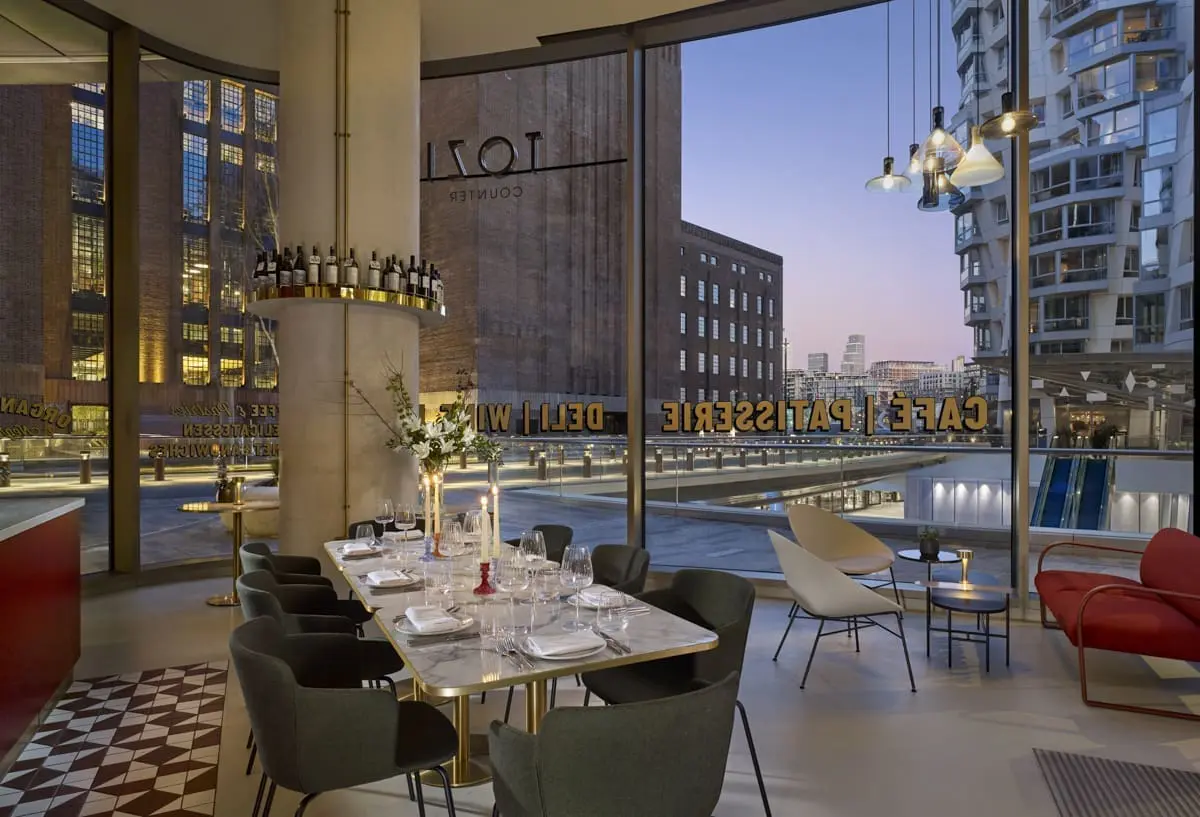 Chic dining space at art'otel Battersea Power Station restaurant & bar featuring marble table, modern chairs, and panoramic city views.