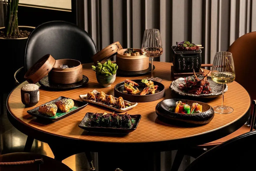 Table filled with gourmet Asian dishes and wine at rome art rooms, showcasing elegant presentation and luxurious dining experience.