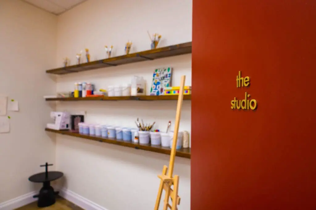 Creative studio space at art'otel Hotel next to Battersea Power Station featuring shelves of paints, brushes, art supplies and an easel.