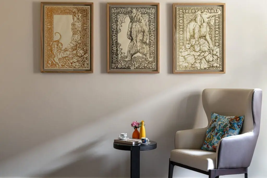 Cozy corner at art gallery art’otel hotel Rome with beige armchair, colorful cushion, framed animal artwork, and coffee table.