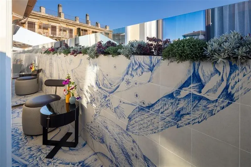 Outdoor terrace at art’otel Rome art hotel with artistic blue wall tiles, modern seating, plants, and city view.