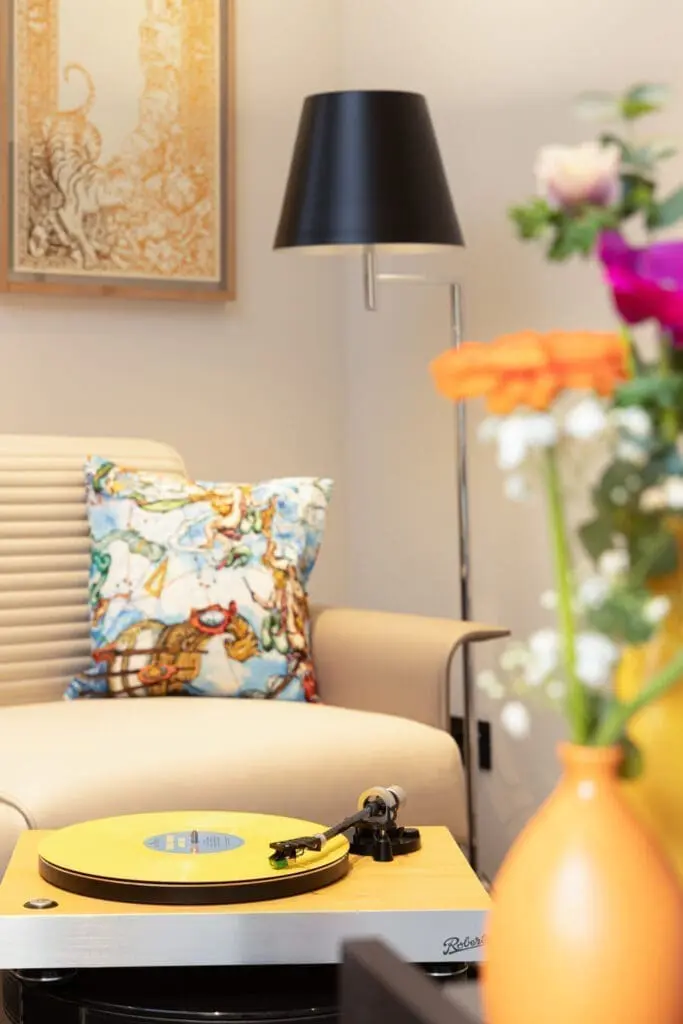 Stylish lounge corner at art gallery art’otel hotel Rome with beige armchair, colorful cushion, and fresh flowers.