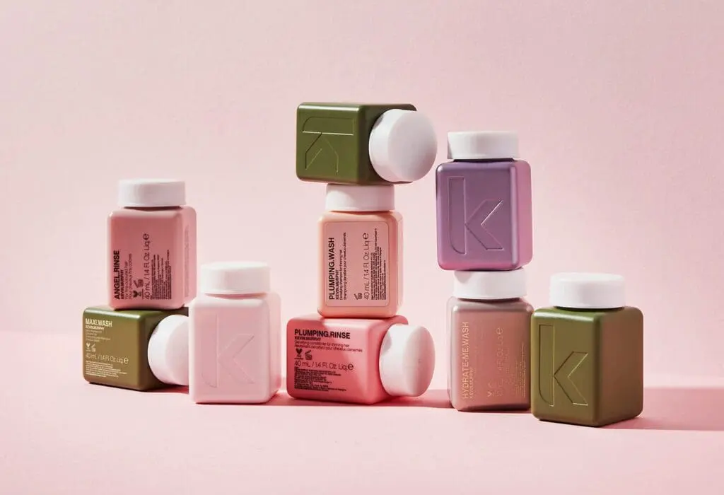 Colourful display of premium miniature haircare bottles arranged artistically on a pink backdrop, reflecting the stylish amenities offered at art'otel Hotel next to Battersea Power Station.