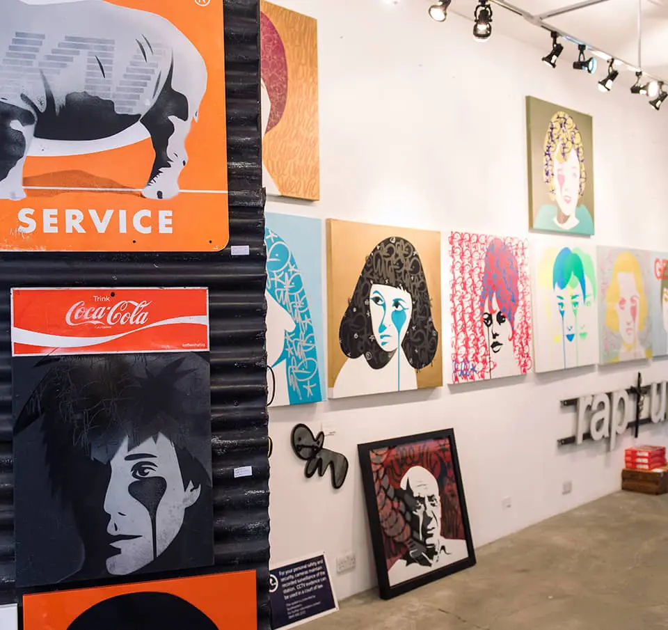 Colorful contemporary artworks displayed at an art exhibition in Shoreditch, featuring vibrant portraits and modern pop art pieces.