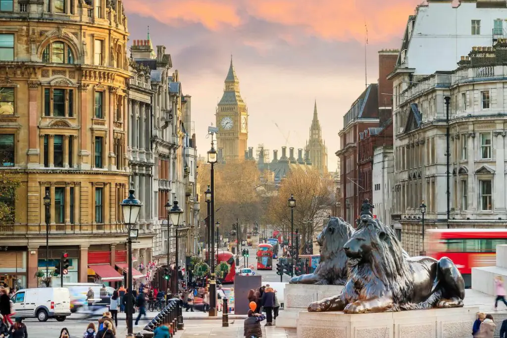 Trafalgar Square Lion Statue, Big Ben and London street scene at sunset with red buses - art'otel
