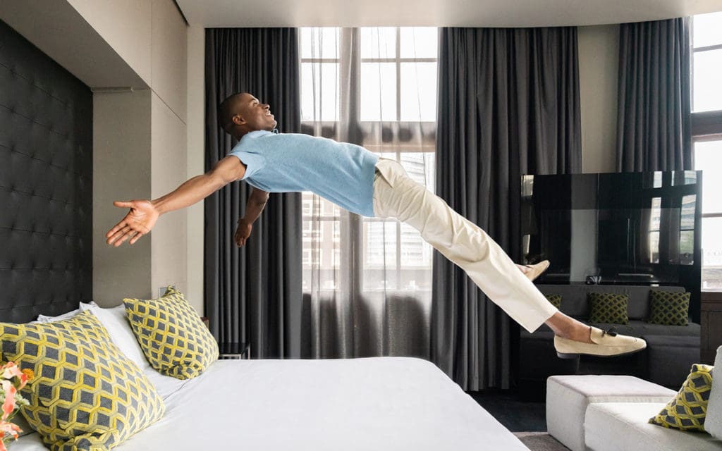 man jumping into bed at art'otel Amsterdam bedroom