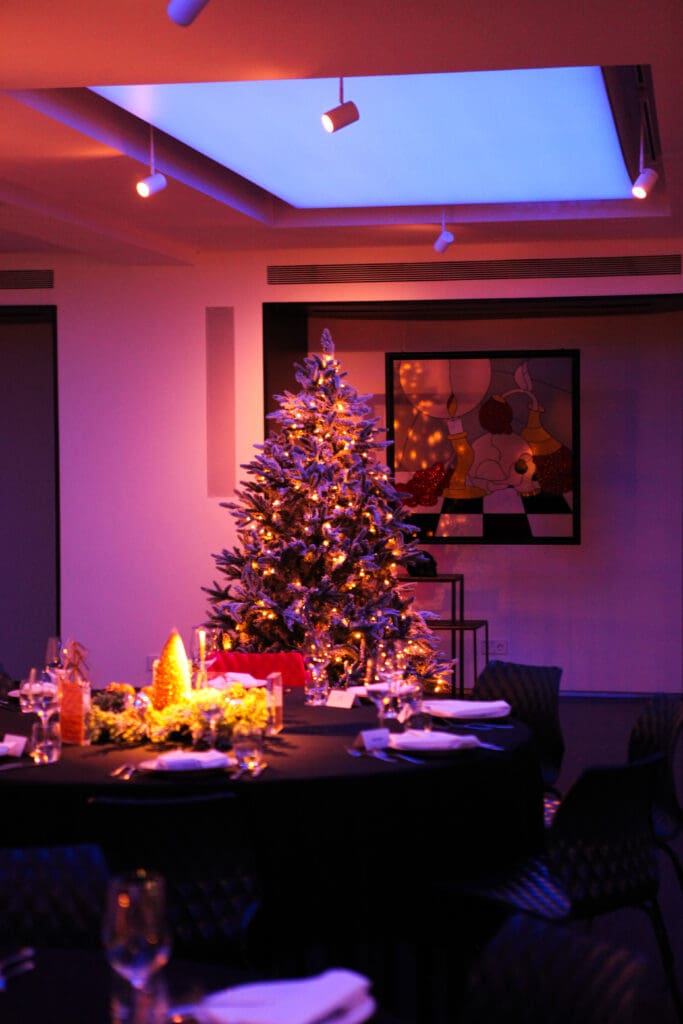 A private dining area at art'otel Amsterdam with a Christmas tree, moody purple lighting, and tables set ready for guests.