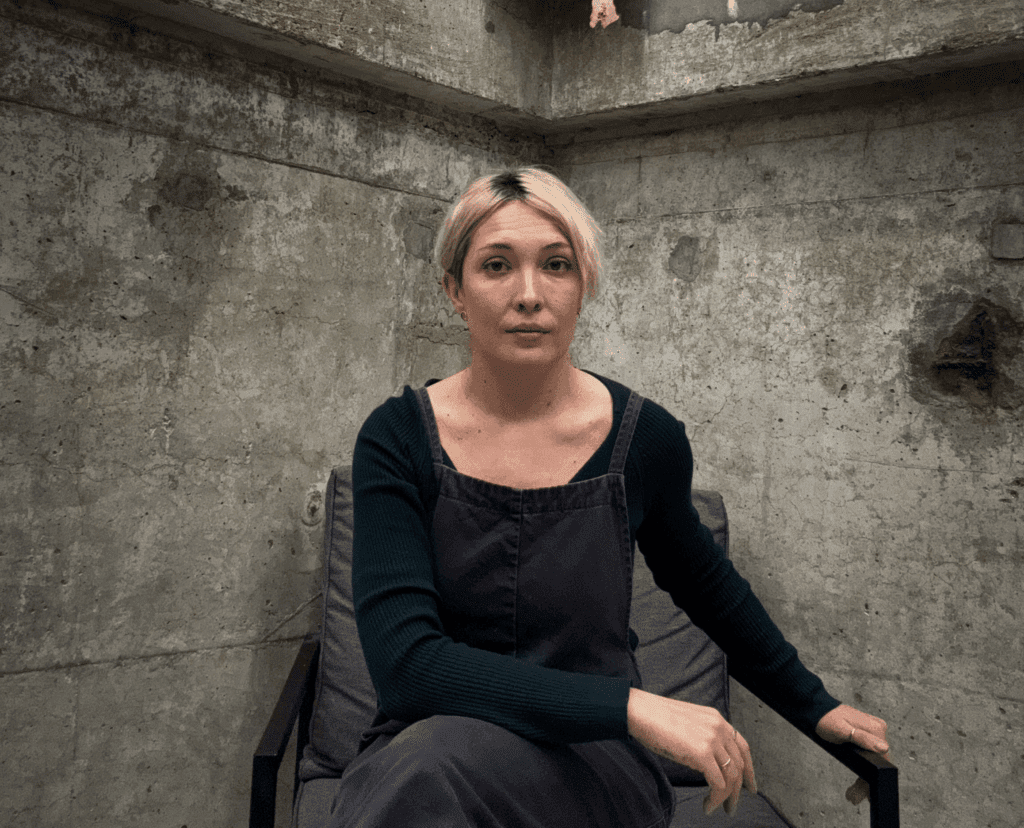Woman seated in concrete room at art exhibition Old Street.